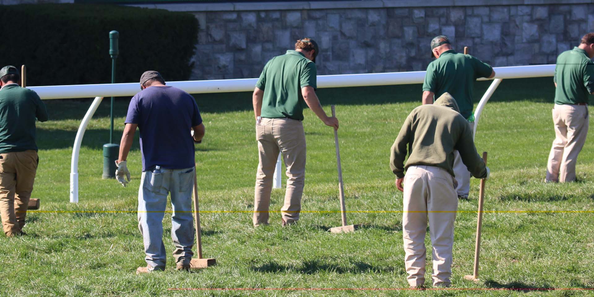 An action shot of Keenjockey team members tamping down turf divots.